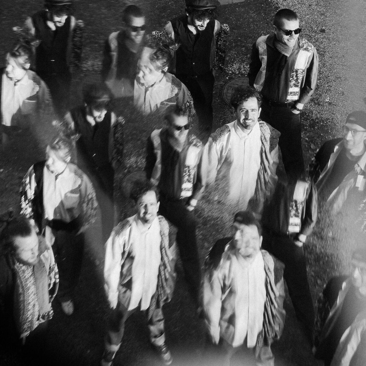 The band seen from above, standing together on the grass, in a black-and-white double exposure.